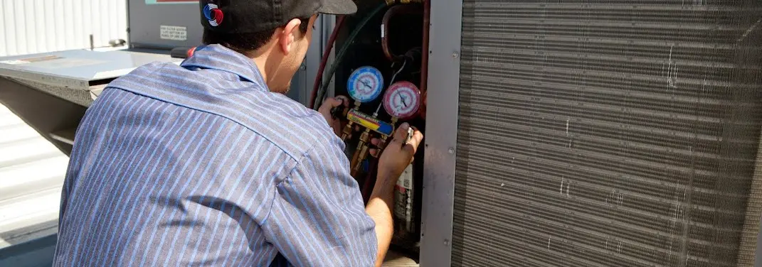 HVAC technician servicing a condenser unit in Somerton